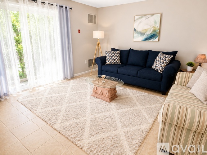A living room with a blue couch and a white rug.