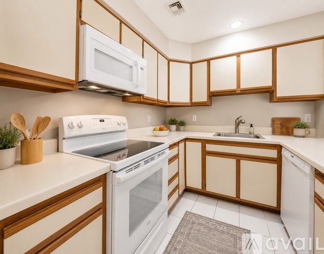 A kitchen with white appliances and wooden cabinets.