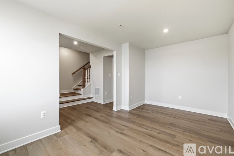A spacious room with wooden flooring and a staircase leading to another room.