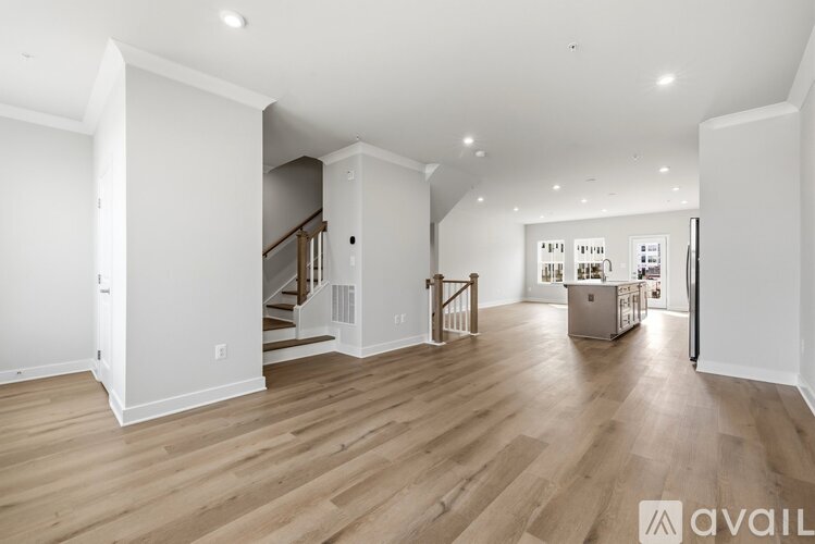 A spacious living room with wooden flooring and white walls.