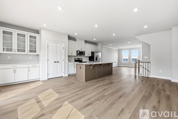 A spacious kitchen with white cabinets and a wooden floor.