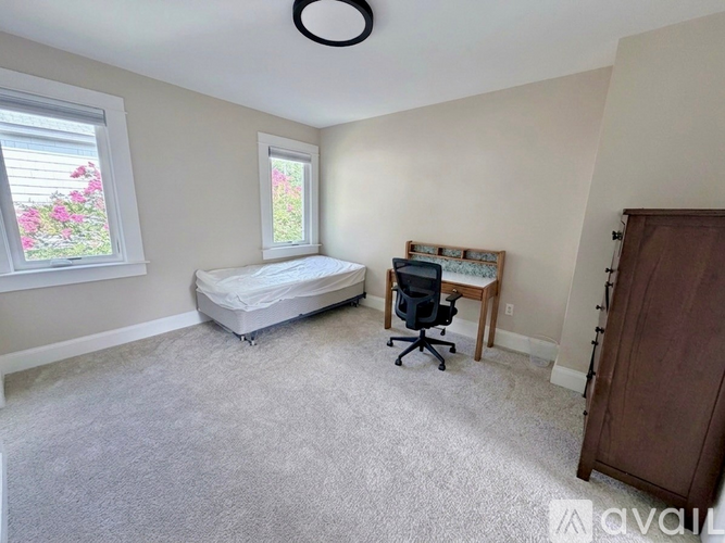 A bedroom with a bed, desk, and window.