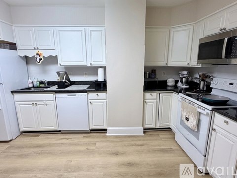 A kitchen with white cabinets and black countertops.