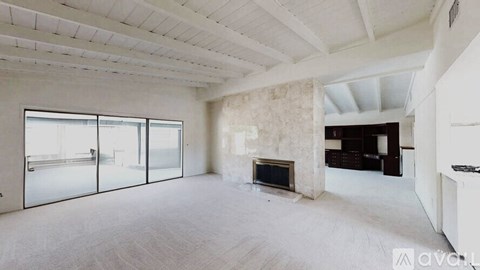 A spacious room with a fireplace and sliding glass doors.