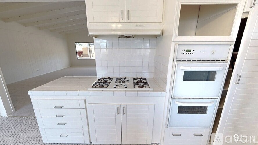 A white kitchen with a stove top oven and a microwave.