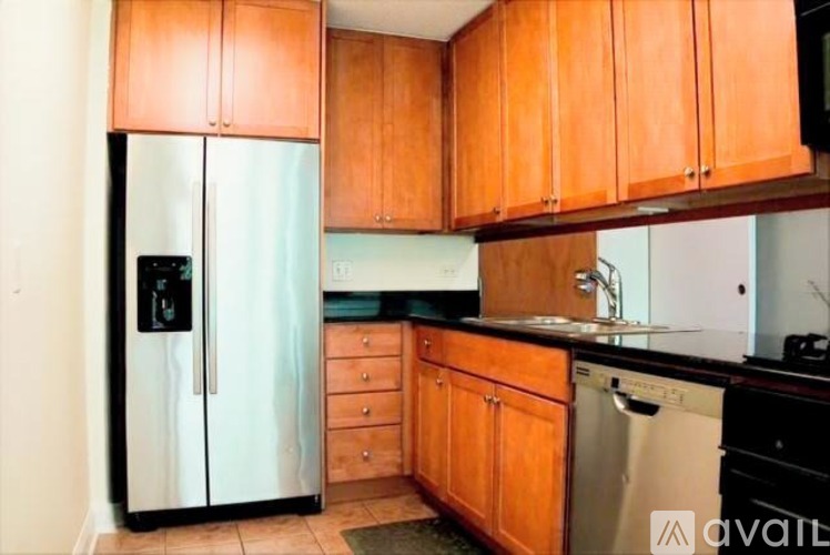 A kitchen with wooden cabinets and a black fridge.