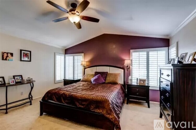 A bedroom with a bed, dresser, and ceiling fan.