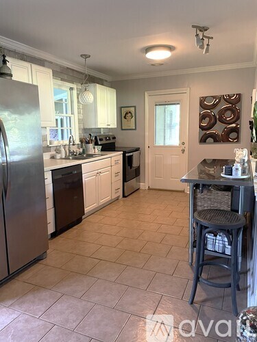 A kitchen with a refrigerator, sink, and cabinets.