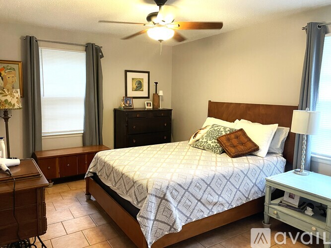 A bedroom with a bed, nightstand, and window with curtains.