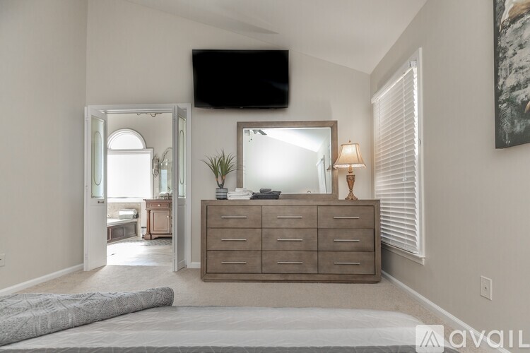 A bedroom with a large bed and a dresser with a mirror above it.