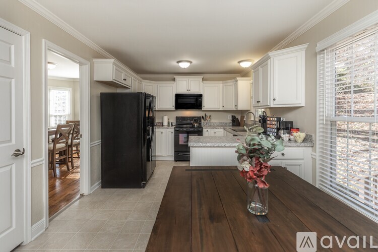 A kitchen with a black refrigerator and white cabinets.