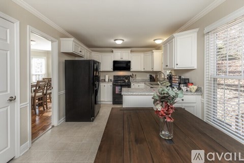 A kitchen with a black refrigerator and white cabinets.