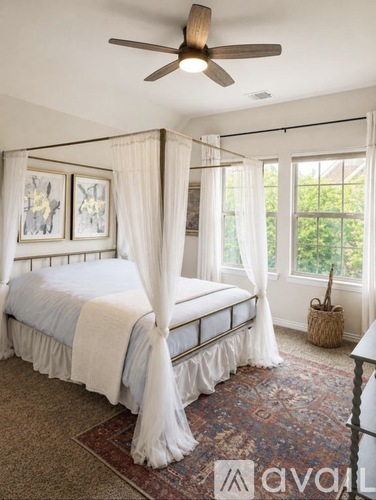 A bedroom with a canopy bed and a ceiling fan.
