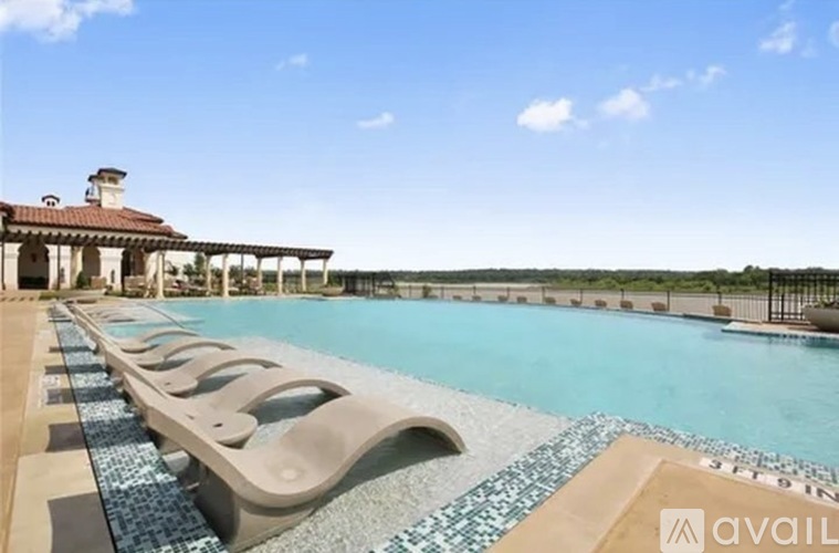 A pool with a tiled edge and a building in the background.
