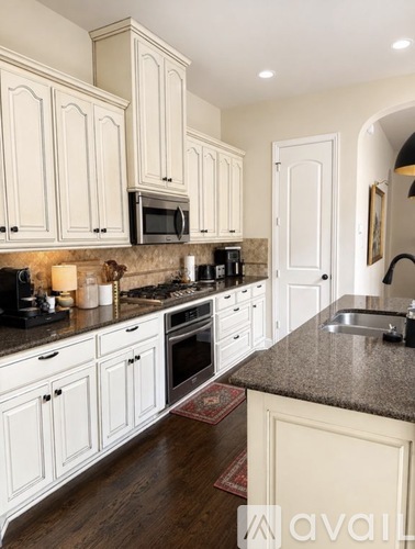 A kitchen with white cabinets and a granite countertop.