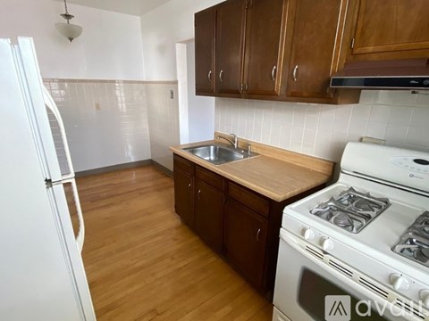 A kitchen with a white stove and wooden cabinets.