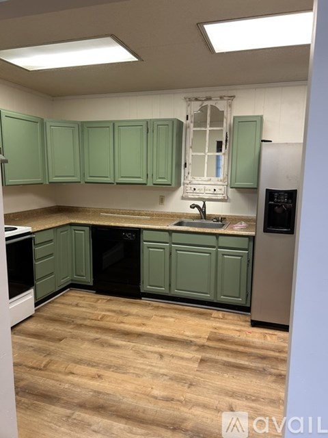 A kitchen with green cabinets and wooden floors.