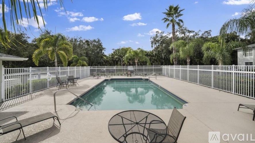 A pool surrounded by a fence and palm trees.