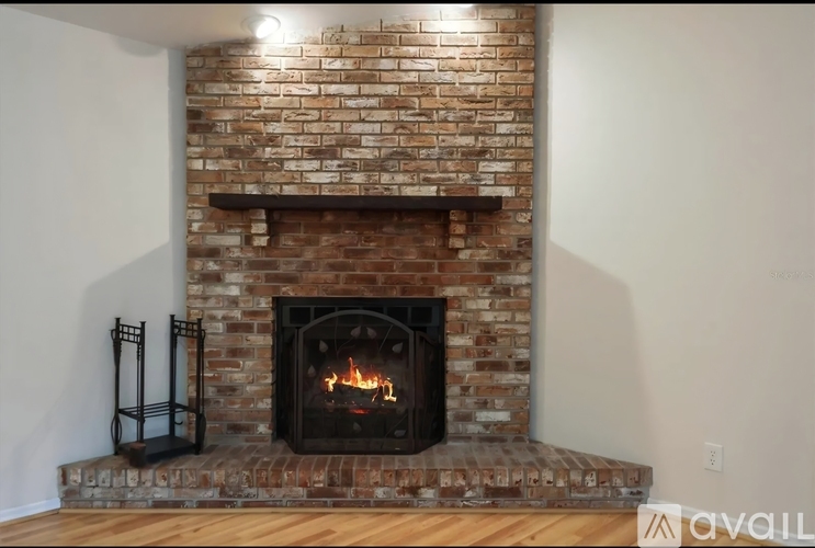 A fireplace with a brick wall and a fire burning inside.