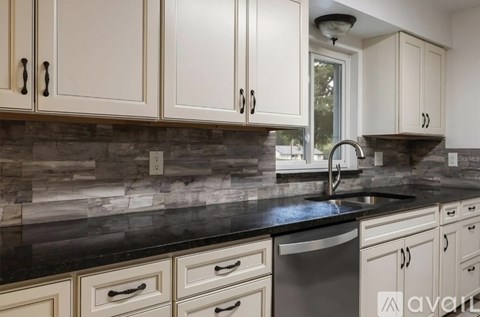 A kitchen with white cabinets and a black countertop.