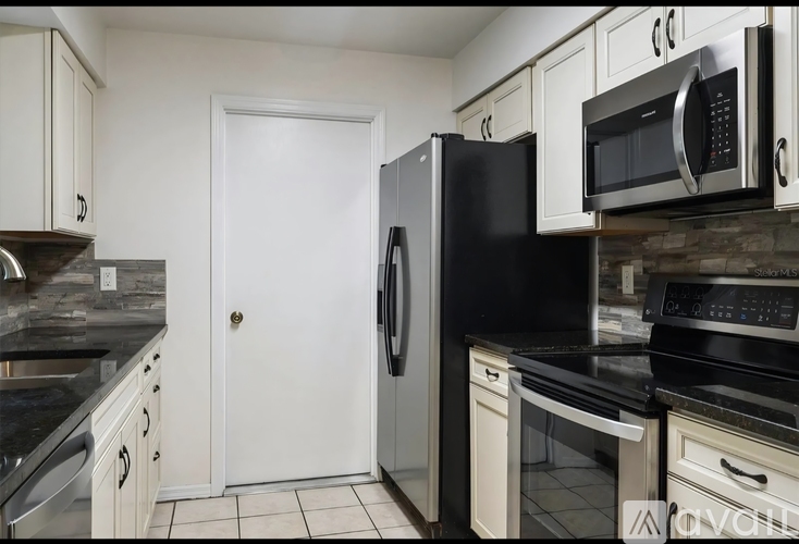A kitchen with black appliances and white cabinets.