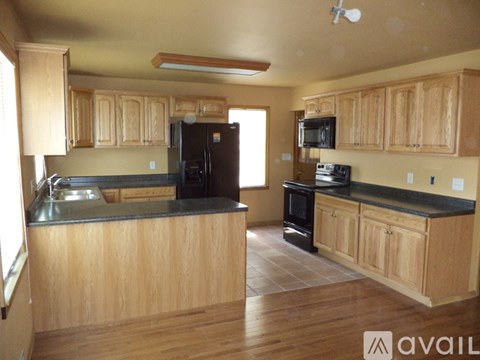 A kitchen with wooden cabinets and black countertops.
