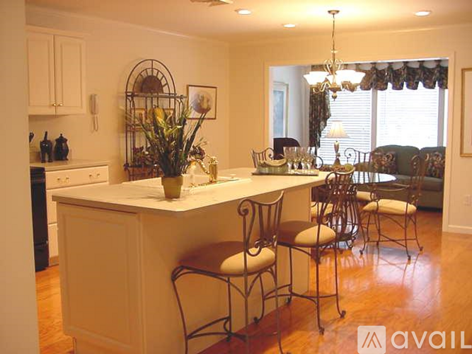 A kitchen with a white island and chairs.