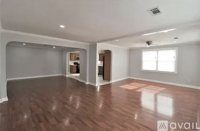 A spacious room with wooden flooring and a ceiling fan.