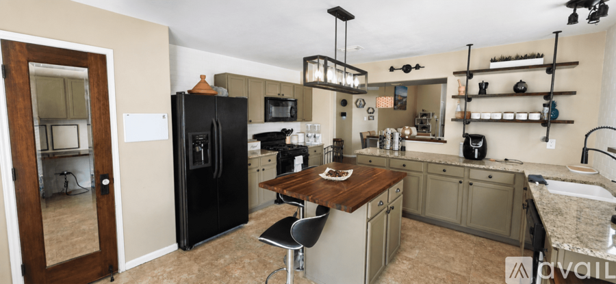 A kitchen with a black refrigerator and a wooden island.