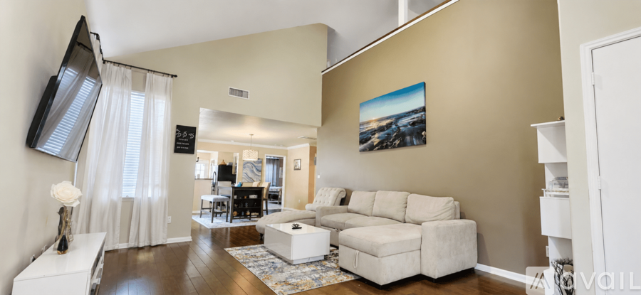 A living room with a white couch and a painting on the wall.