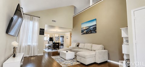 A living room with a white couch and a painting on the wall.