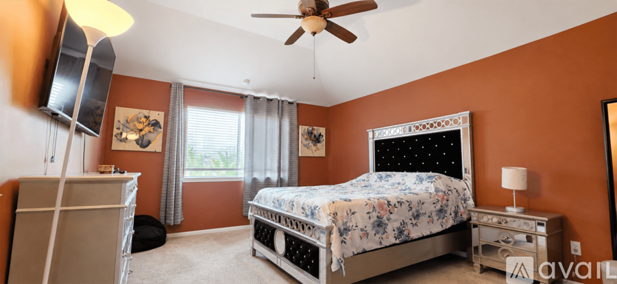 A bedroom with orange walls and a large bed with a black headboard.