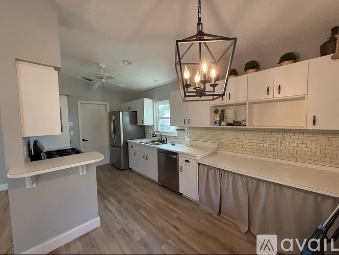A kitchen with white cabinets and a wooden floor.