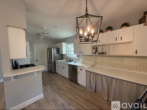 A kitchen with white cabinets and a wooden floor.