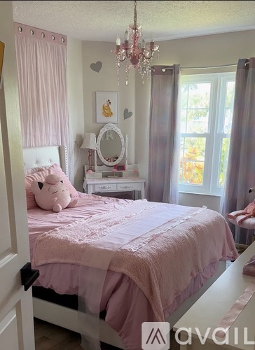 A pink bedroom with a chandelier and a teddy bear on the bed.