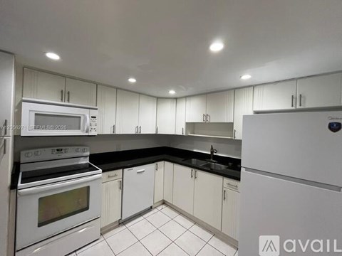 A kitchen with white cabinets and black countertops.