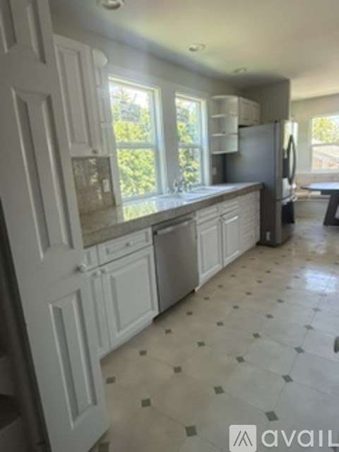 A kitchen with white cabinets and a tiled floor.