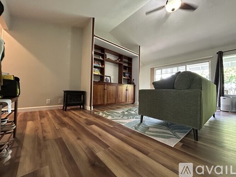 A living room with a green couch and a wooden floor.