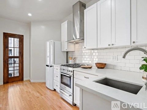 A kitchen with white cabinets and a stainless steel range hood.
