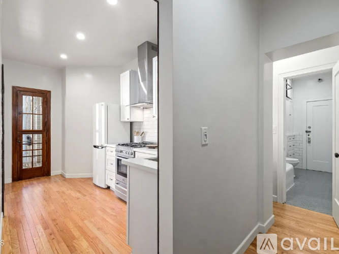 A kitchen with white appliances and wooden floors.