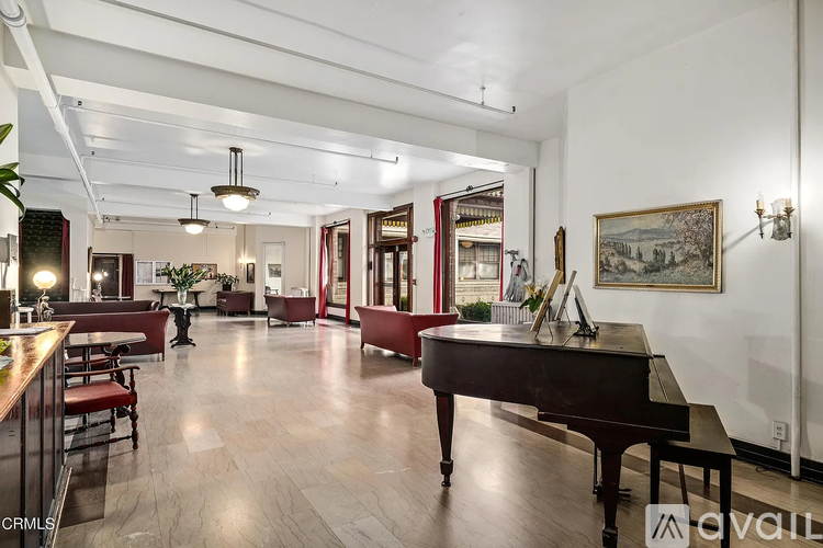 A large room with a piano in the middle and a person standing in the background.