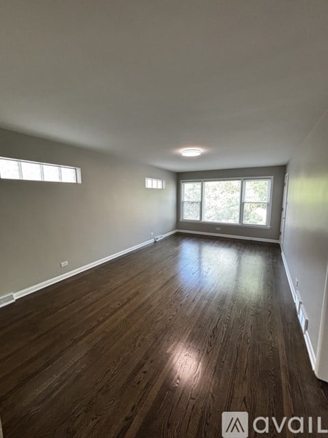A room with wooden flooring and two windows.