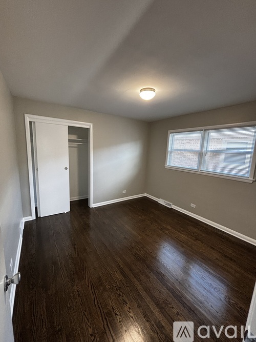 A room with wooden floors and a window with blinds.