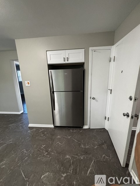 A kitchen with a stainless steel refrigerator and a white door.