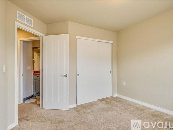 A bedroom with a carpeted floor and two closet doors.