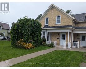 A house with a white front porch and a large green bush in front.