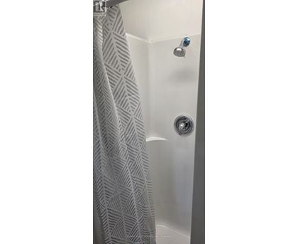 A shower curtain with a diamond pattern hangs over a bathtub.