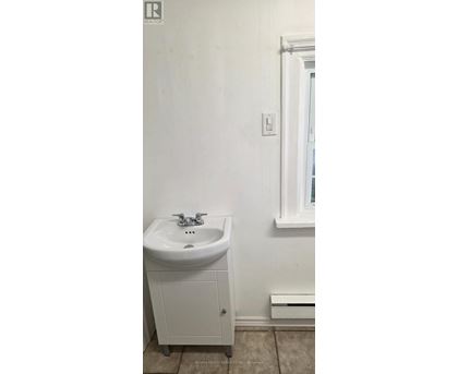 A white bathroom with a sink and a cabinet.