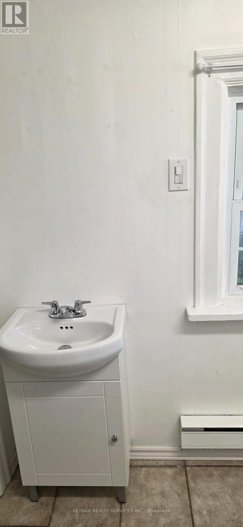 A white bathroom with a sink and a cabinet.