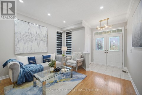 A living room with a glass coffee table and a large painting on the wall.